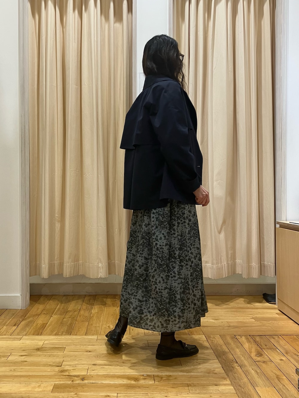 ブラック系のスカート、ブルー系のトレンチコート、グレー系のニット/セーターを着用したレディースの春コーディネートの3枚目の写真