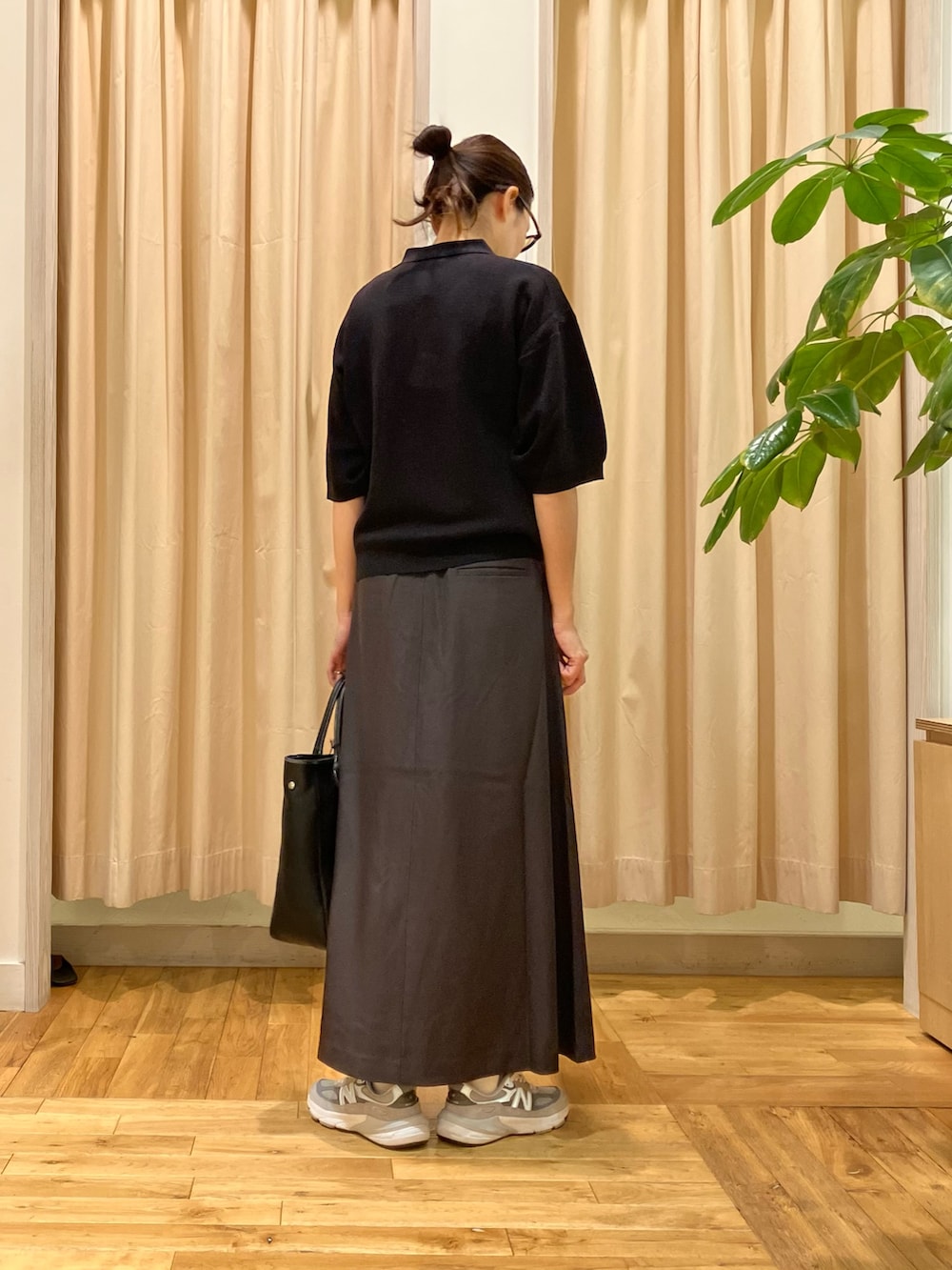 ブラック系のポロシャツ、グレー系のスカート、ブラック系のトートバッグを着用したレディースの秋コーディネートの4枚目の写真