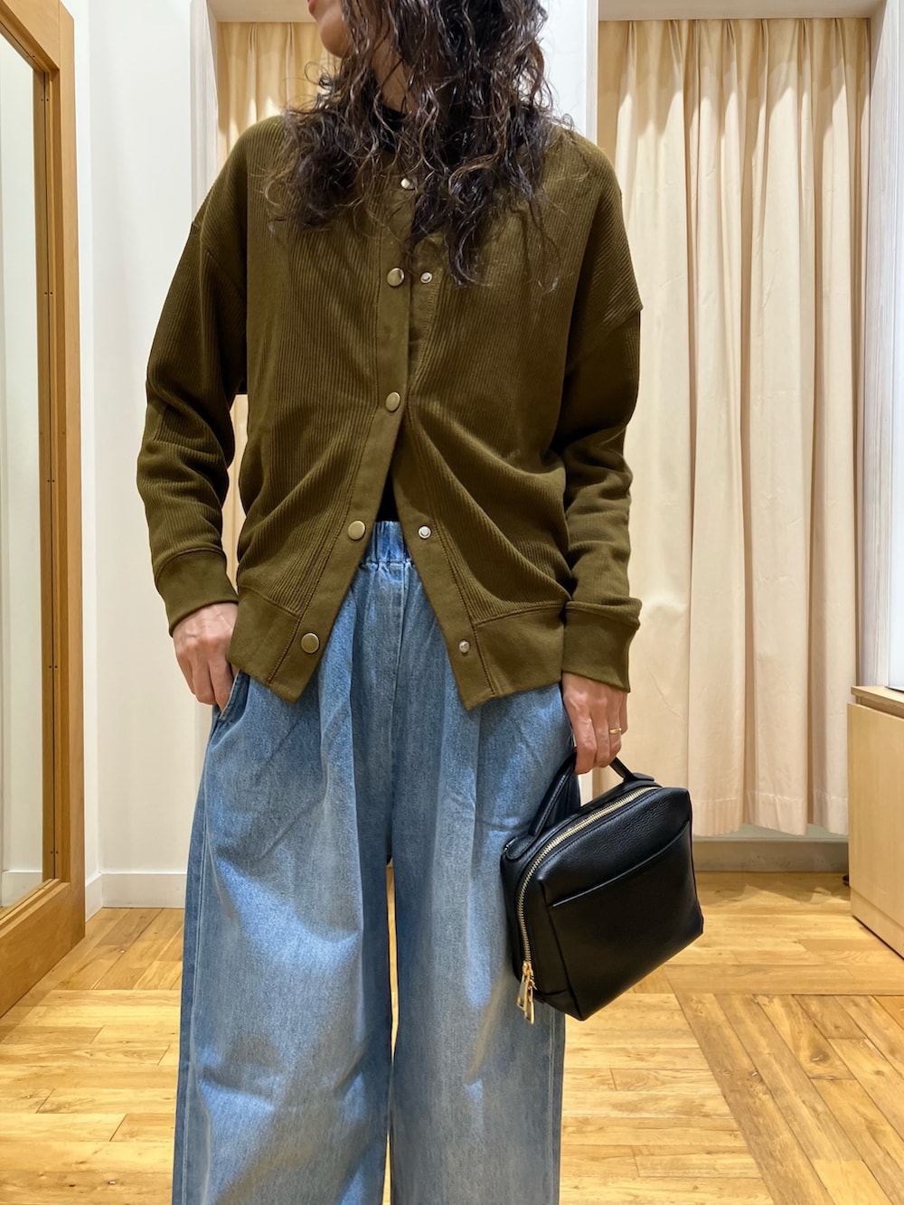 ブラウン系のカーディガン/ボレロ、ブラック系のTシャツ/カットソー、ブルー系のデニムパンツを着用したレディースの秋コーディネートの4枚目の写真