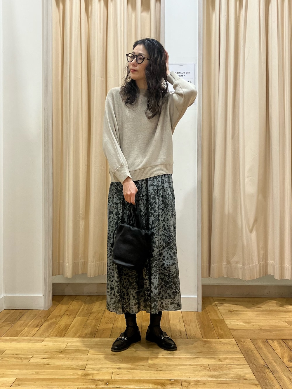 ブラック系のスカート、ブルー系のトレンチコート、グレー系のニット/セーターを着用したレディースの春コーディネートの6枚目の写真