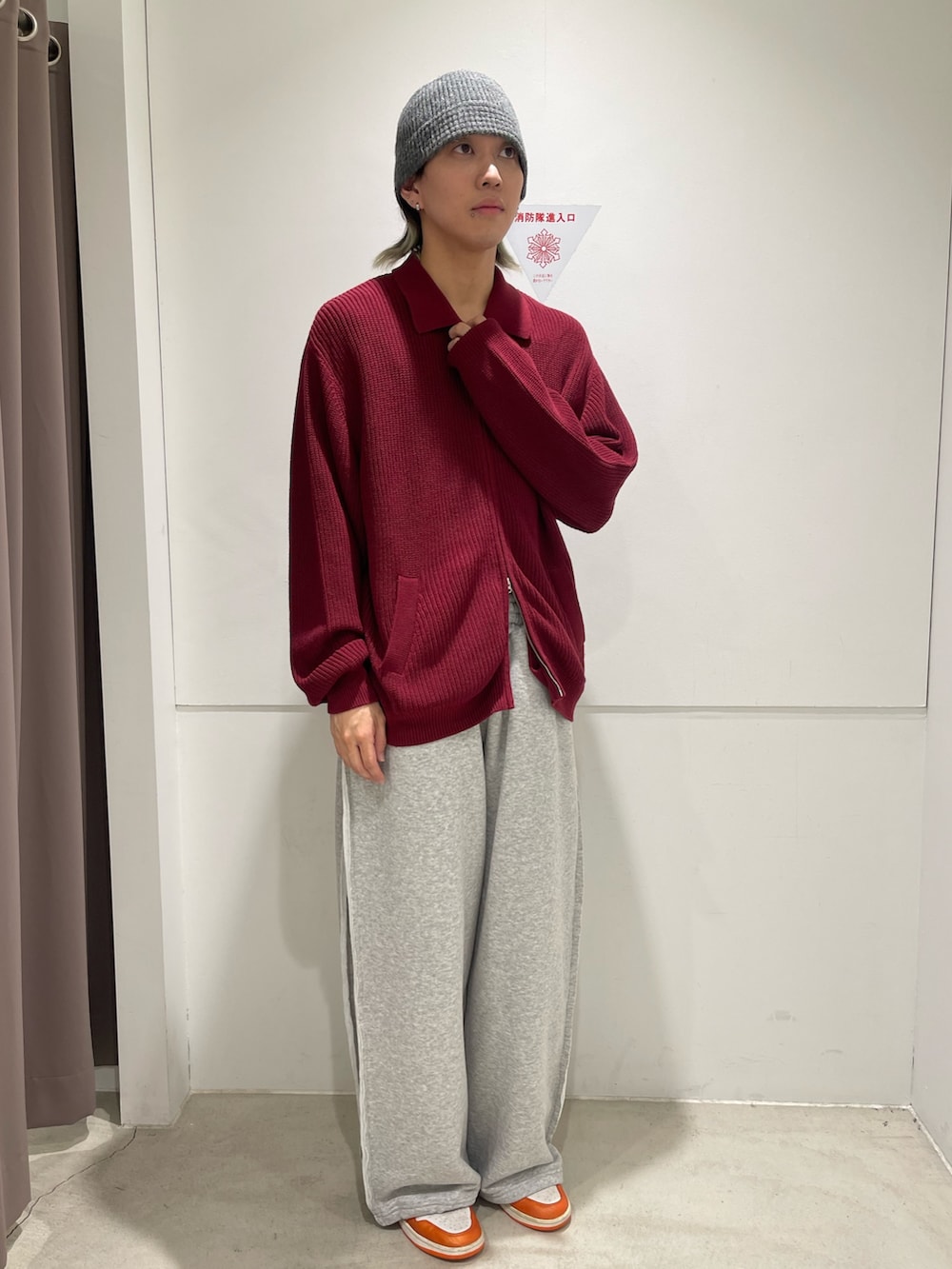 レッド系のニット/セーター、グレー系のパンツを着用したメンズの秋コーディネートの2枚目の写真
