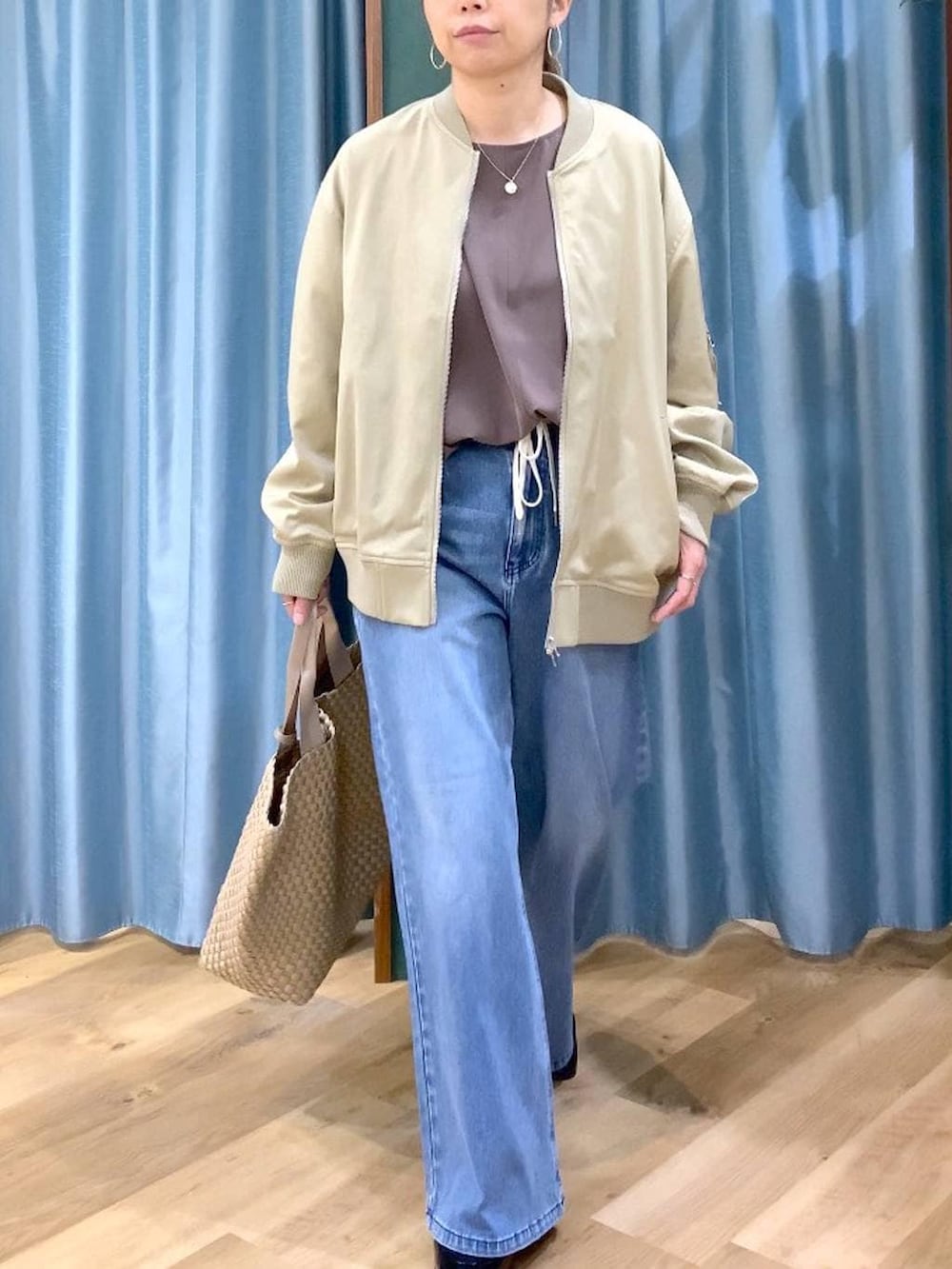 ブルー系のデニムパンツ、ベージュ系のMA-1、グリーン系のTシャツ/カットソーを着用したレディースの冬コーディネートの7枚目の写真