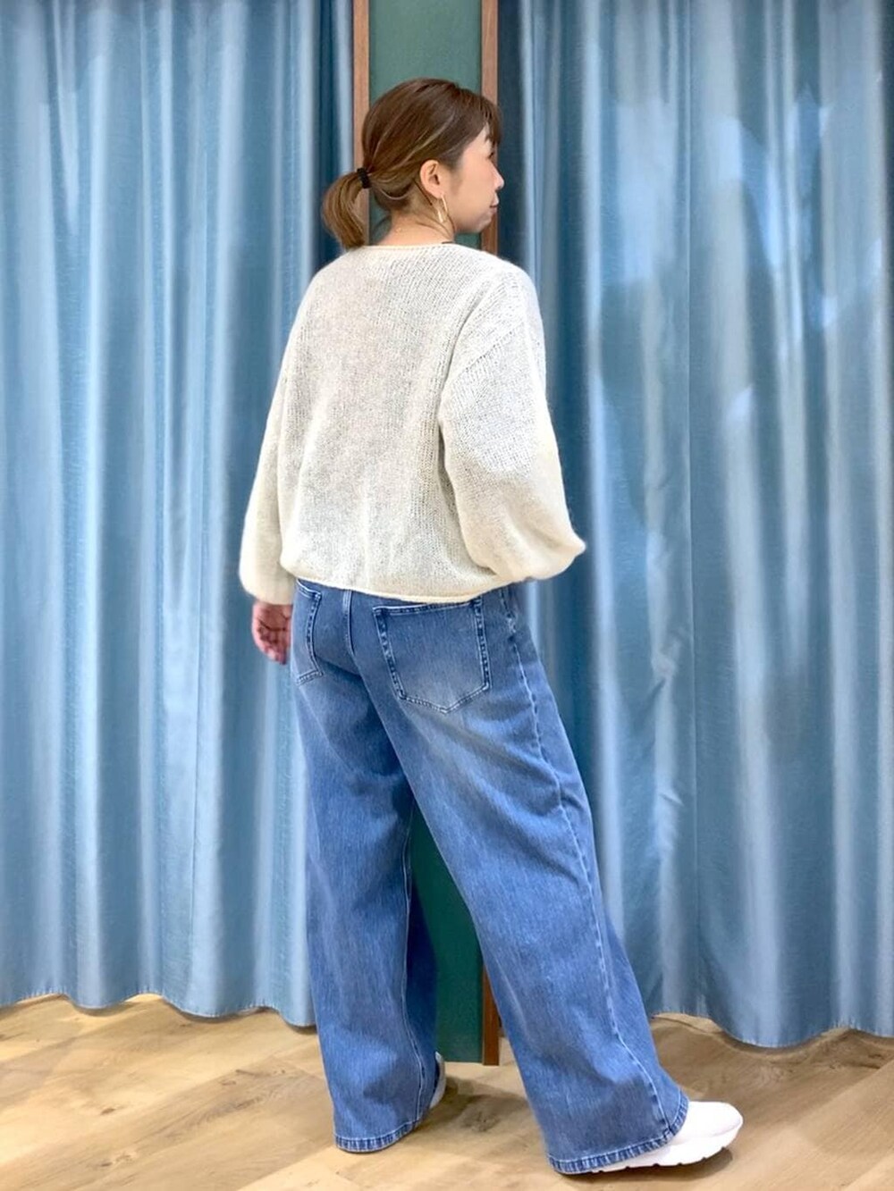 ブルー系のデニムパンツ、ホワイト系のニット/セーター、ホワイト系のスニーカーを着用したレディースの冬コーディネートの2枚目の写真