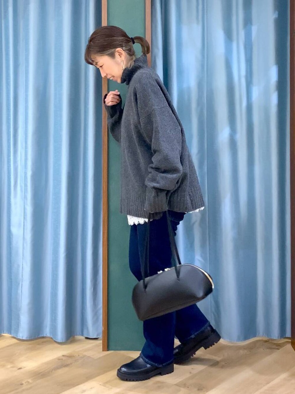 ブラック系のトートバッグ、ブラック系のブーツ、ブルー系のデニムパンツを着用したレディースの秋コーディネートの3枚目の写真