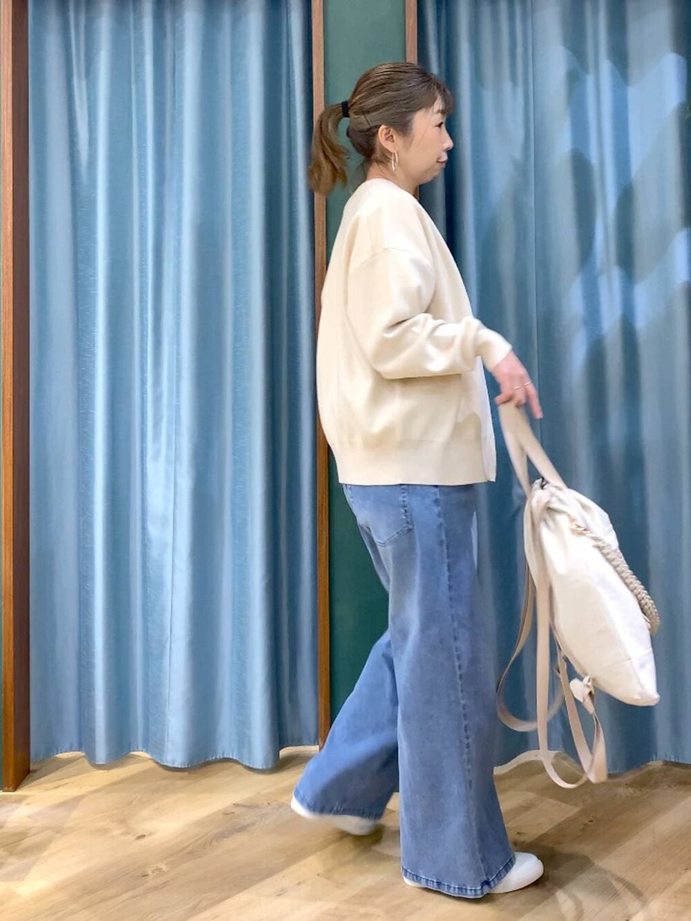 ホワイト系のカーディガン/ボレロ、ブルー系のデニムパンツ、ホワイト系のTシャツ/カットソーを着用したレディースの冬コーディネートの4枚目の写真