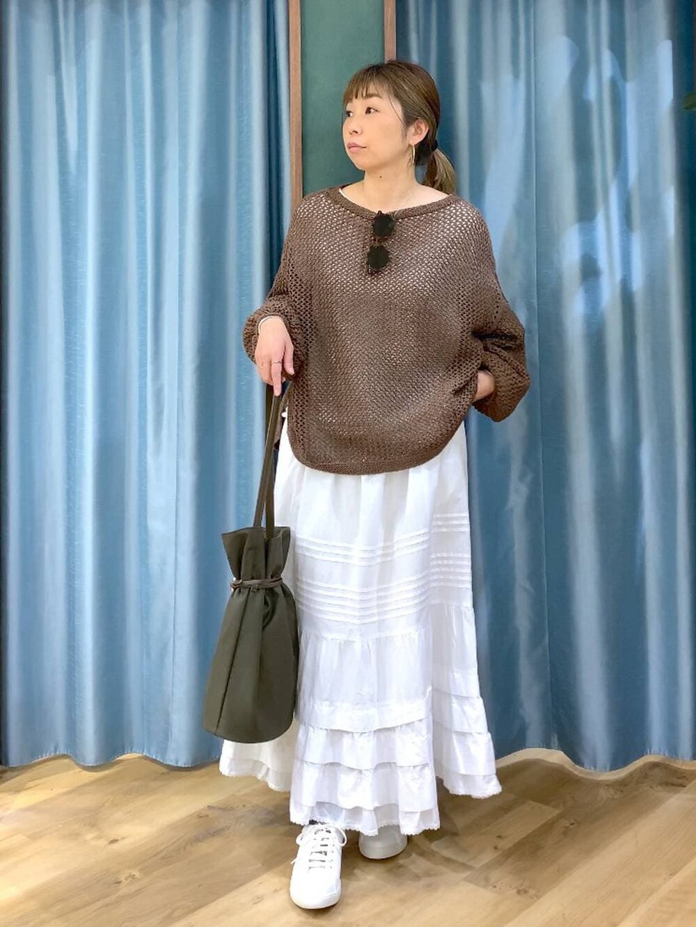 ブラウン系のスニーカー、ブラウン系のニット/セーター、ホワイト系のスカートを着用したレディースの冬コーディネートの2枚目の写真