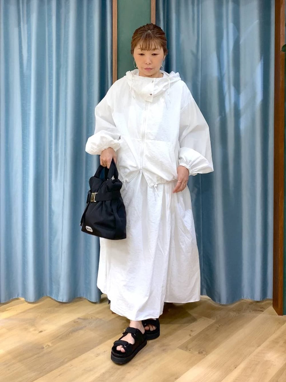 ホワイト系のスカート、ホワイト系のブルゾン、ブラック系のトートバッグを着用したレディースの春コーディネートの3枚目の写真