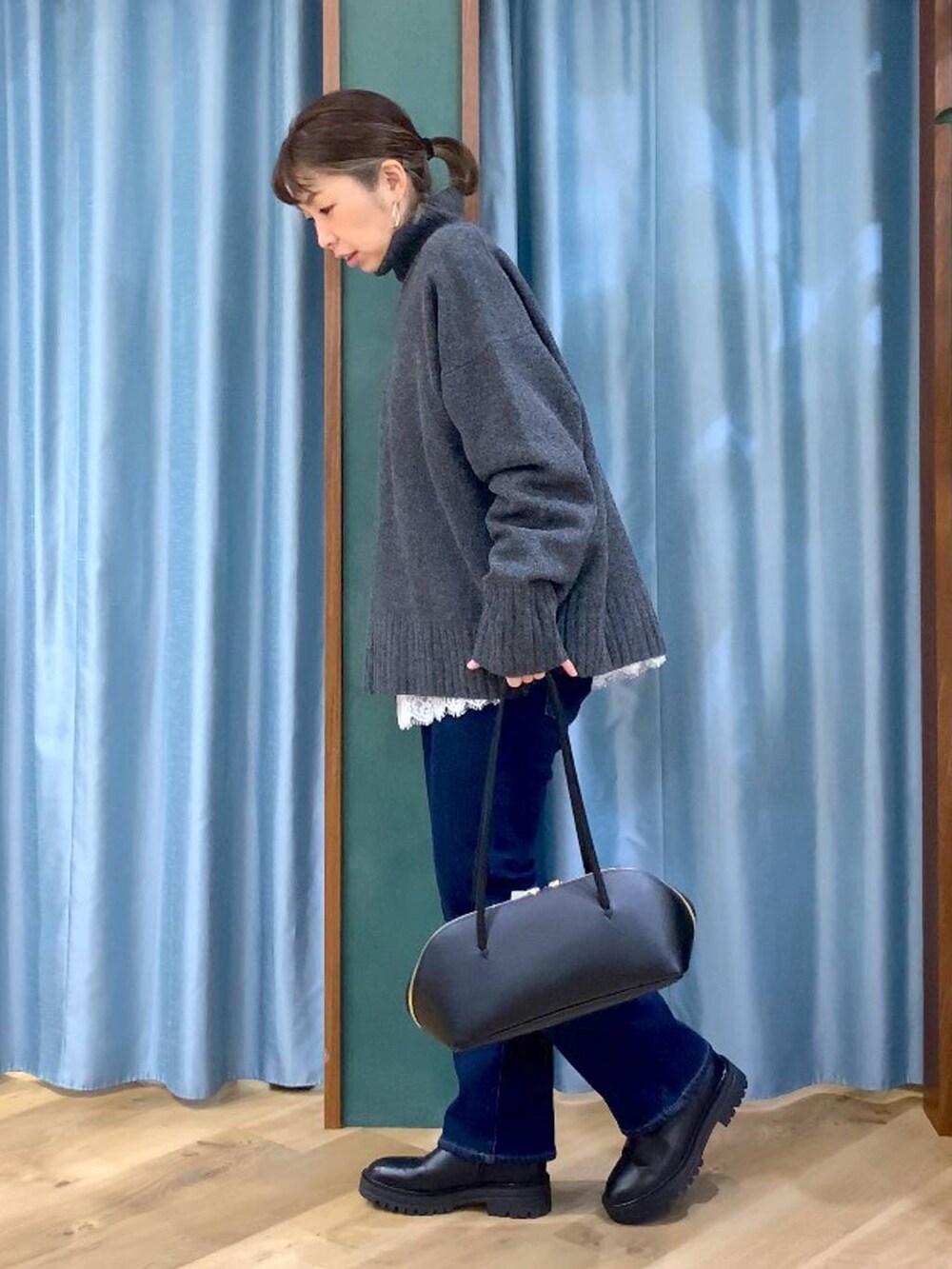 ブラック系のトートバッグ、ブラック系のブーツ、ブルー系のデニムパンツを着用したレディースの秋コーディネートの5枚目の写真