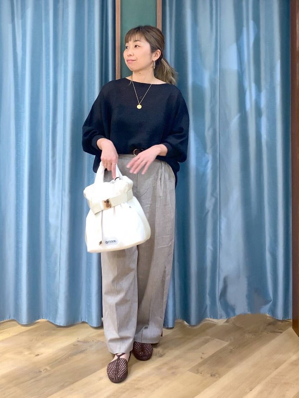 ブラック系のニット/セーター、ベージュ系のその他パンツ、ホワイト系のトートバッグを着用したレディースの春コーディネートの5枚目の写真