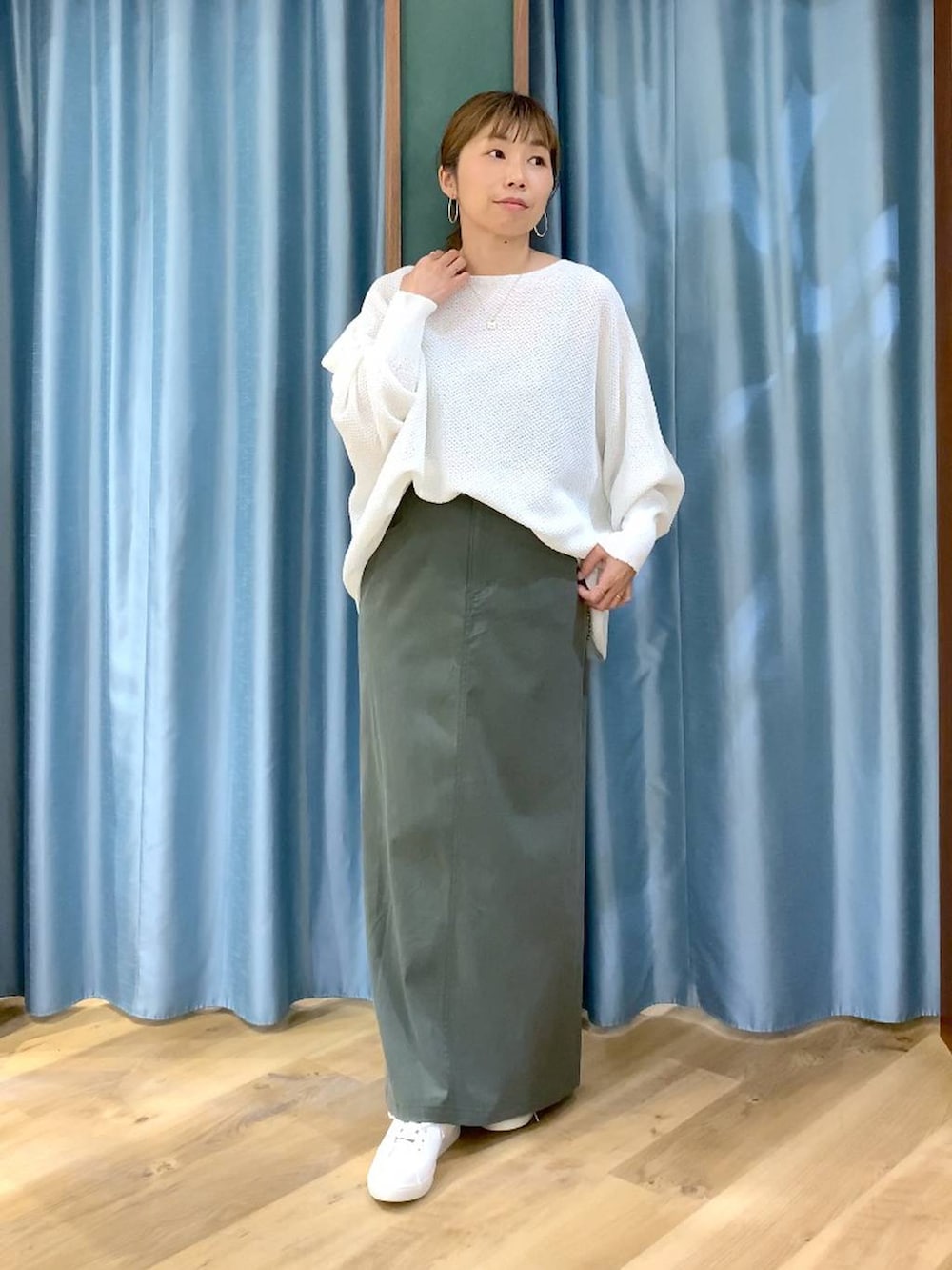 ホワイト系のニット/セーター、グリーン系のスカート、ブラウン系のスニーカーを着用したレディースの春コーディネートの3枚目の写真