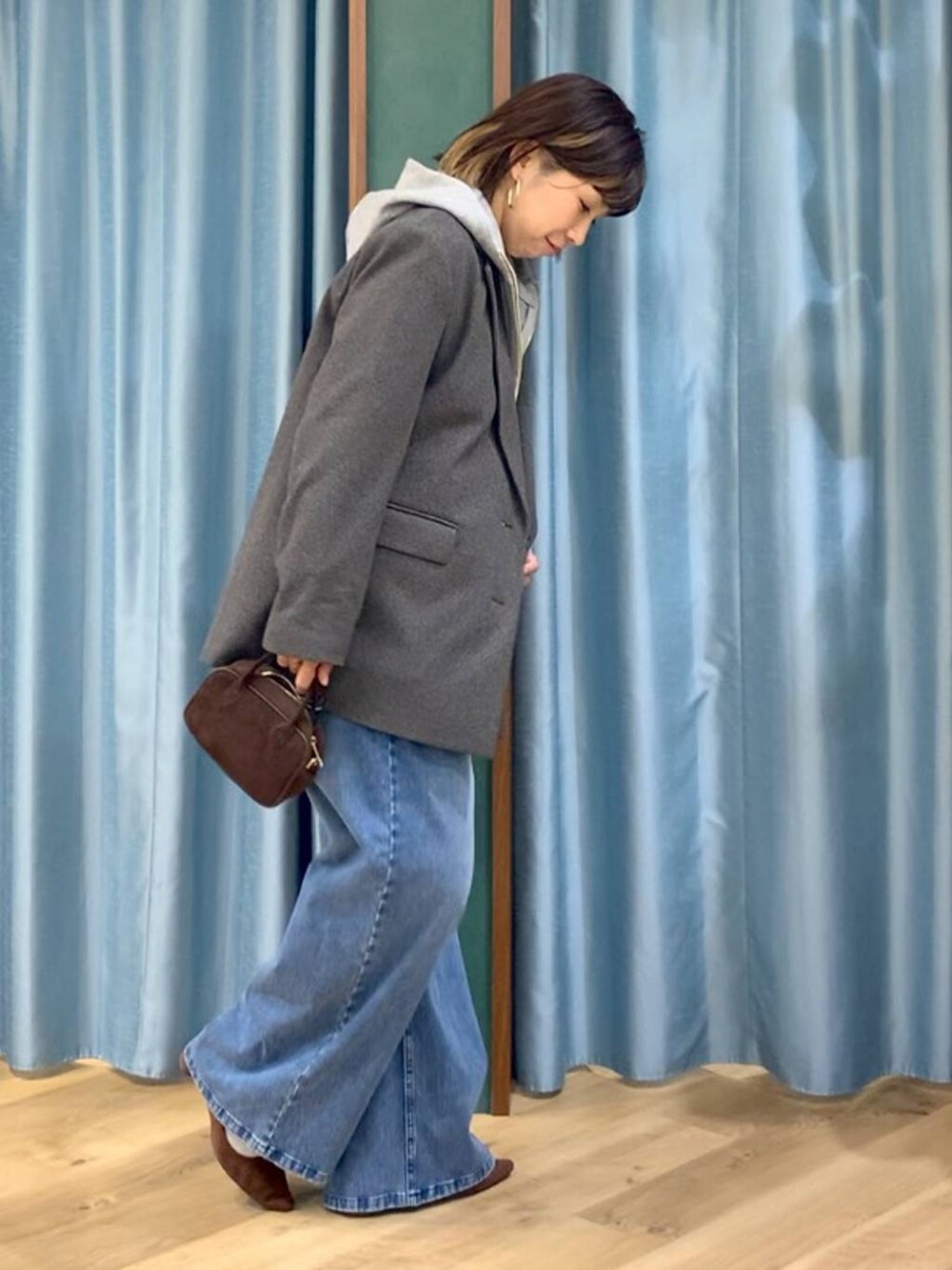 ブルー系のデニムパンツ、ブラウン系のテーラードジャケット、グレー系のパーカーを着用したレディースの秋コーディネートの2枚目の写真