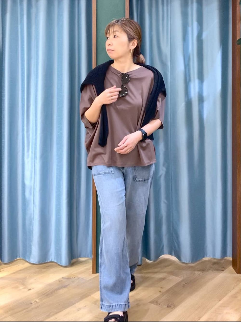 ブラウン系のTシャツ/カットソー、ブルー系のデニムパンツ、ブラック系のニット/セーターを着用したレディースの春コーディネートの5枚目の写真