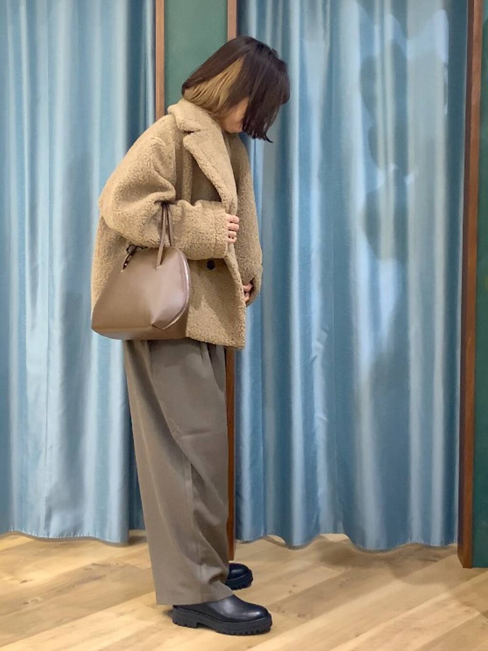 ブラック系のブーツ、ベージュ系のピーコート、ブラウン系のトートバッグを着用したレディースの秋コーディネートの5枚目の写真