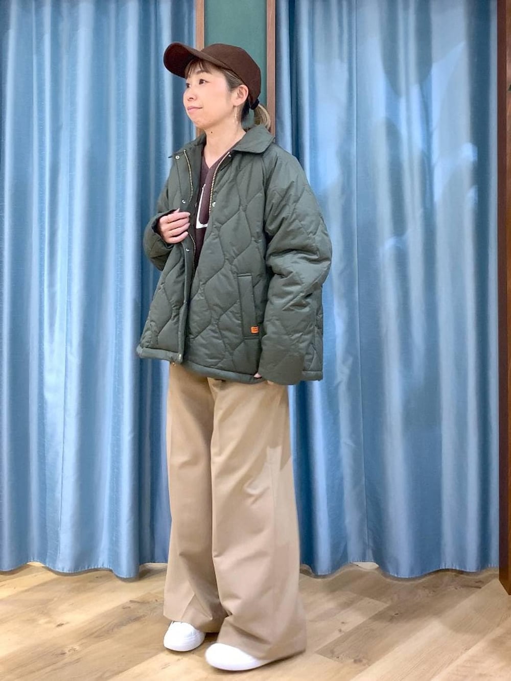 グリーン系のブルゾン、ブラウン系のニット/セーター、イエロー系のスラックスを着用したレディースの冬コーディネートの3枚目の写真