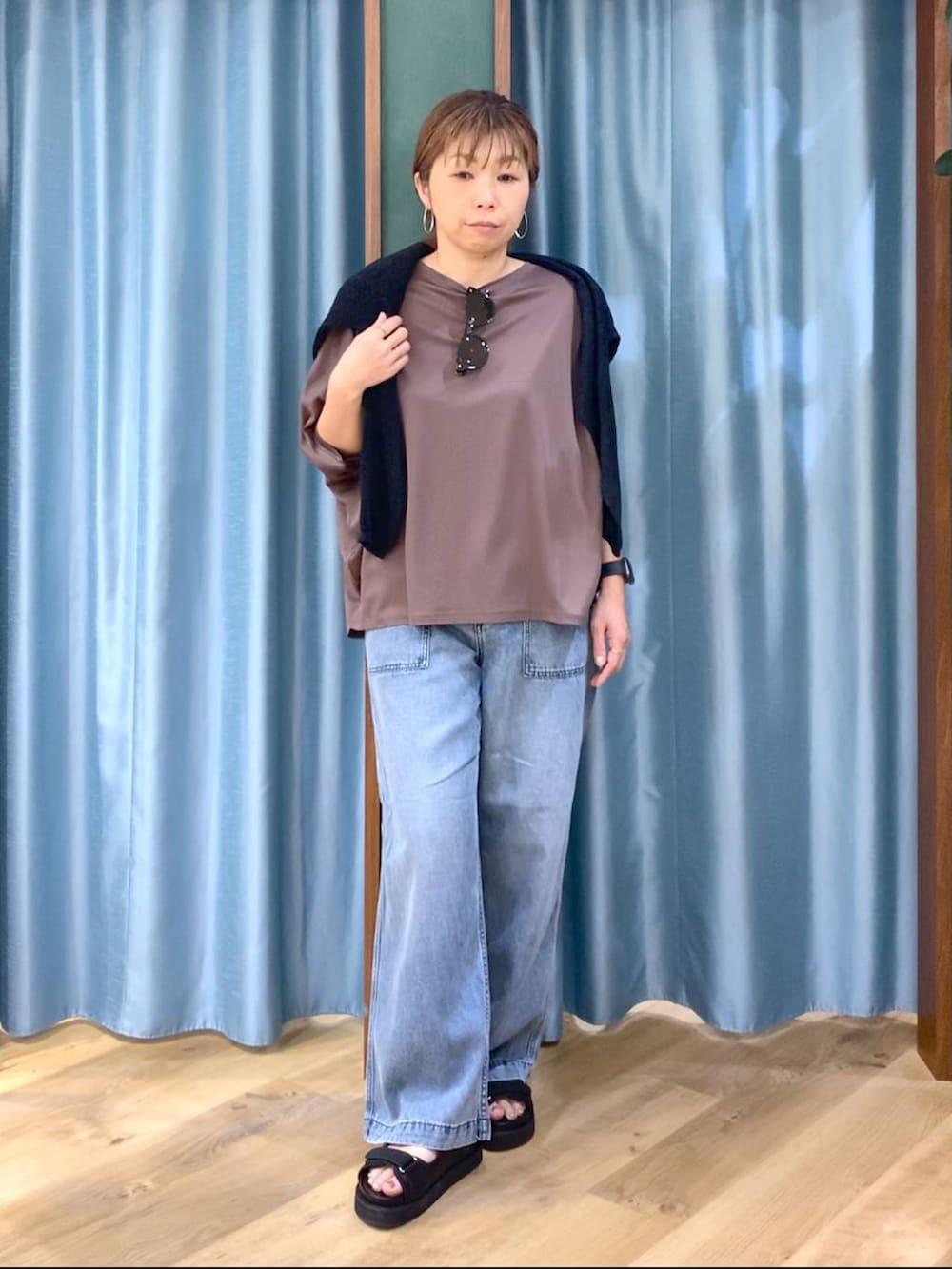 ブラウン系のTシャツ/カットソー、ブルー系のデニムパンツ、ブラック系のニット/セーターを着用したレディースの春コーディネートの2枚目の写真