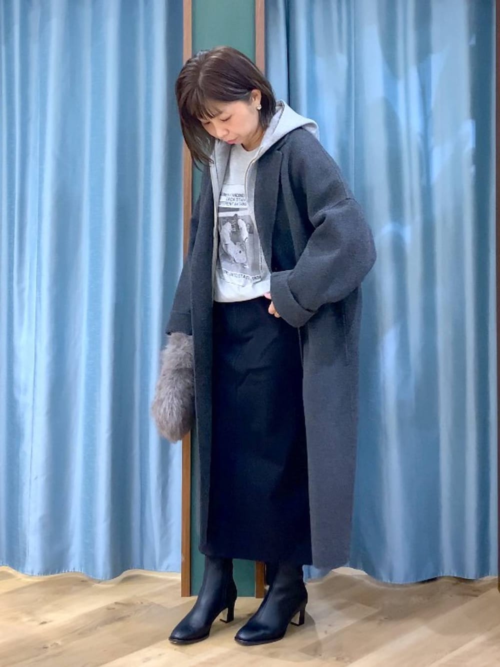 ブラウン系のトートバッグ、グレー系のチェスターコート、ブラック系のスカートを着用したレディースの秋コーディネートの4枚目の写真