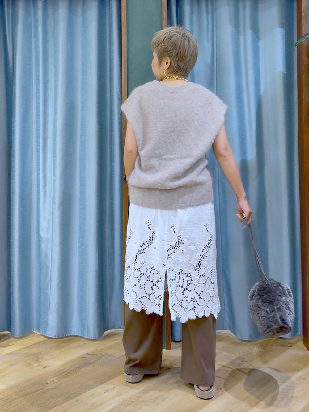 グレー系のハンドバッグ、ホワイト系のチュニック、ブラウン系のデニムパンツを着用したレディースの夏コーディネートの6枚目の写真