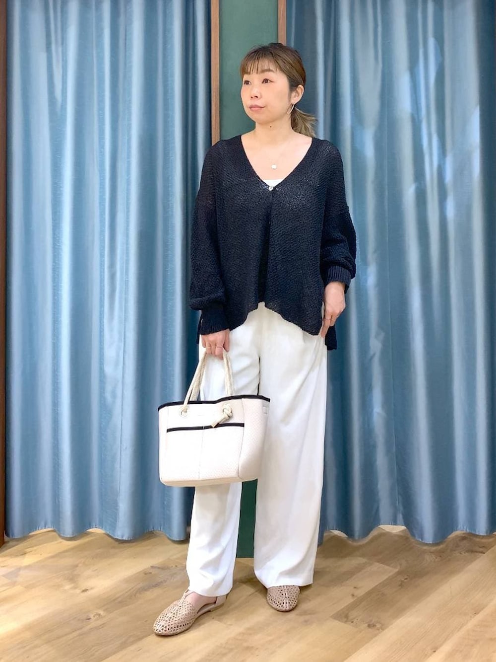ホワイト系のスラックス、ブラック系のカーディガン/ボレロ、ホワイト系のトートバッグを着用したレディースの春コーディネートの2枚目の写真