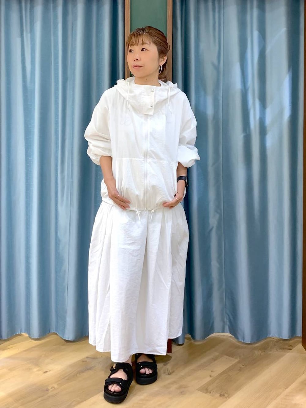 ホワイト系のスカート、ホワイト系のブルゾン、ブラック系のトートバッグを着用したレディースの春コーディネートの2枚目の写真