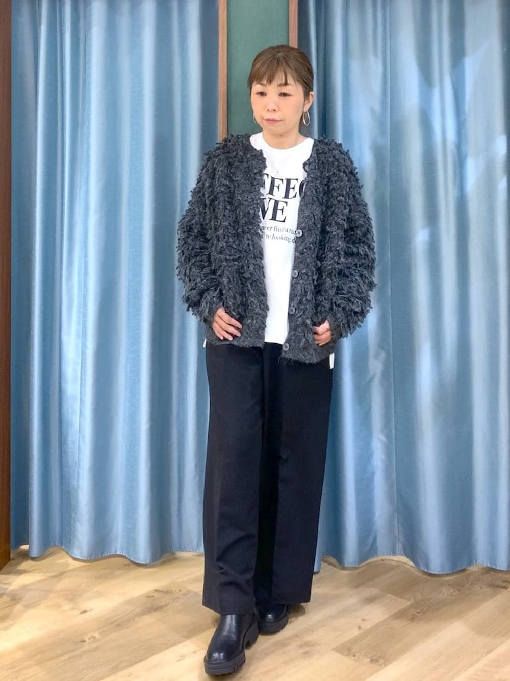 ブラック系のブーツ、ブラック系のスラックス、グレー系のカーディガン/ボレロを着用したレディースの冬コーディネートの2枚目の写真