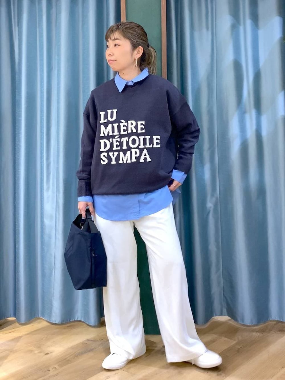 ホワイト系のスラックス、ブルー系のトートバッグ、グレー系のニット/セーターを着用したレディースの冬コーディネートの2枚目の写真