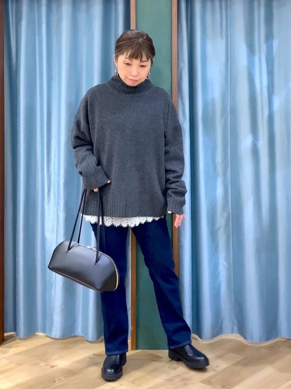 ブラック系のトートバッグ、ブラック系のブーツ、ブルー系のデニムパンツを着用したレディースの秋コーディネートの2枚目の写真