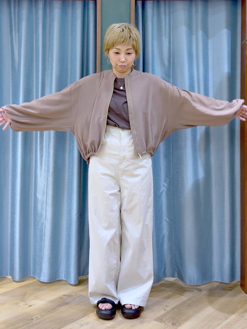 イエロー系のブルゾン、ベージュ系のその他パンツ、ブラック系のサンダルを着用したレディースの夏コーディネートの4枚目の写真