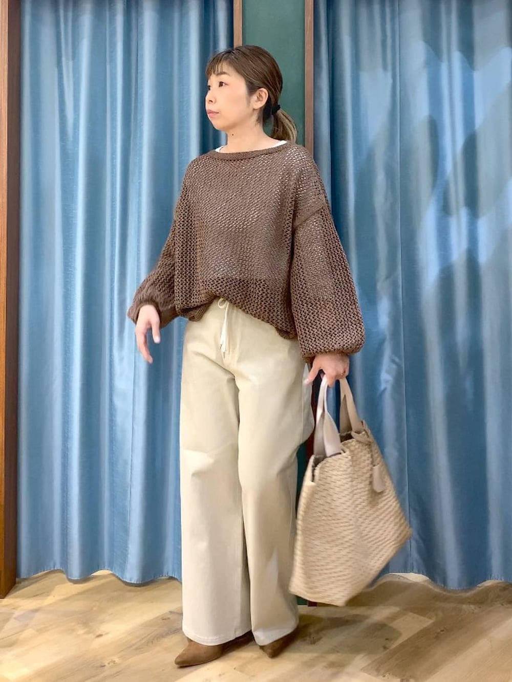 ブラウン系のニット/セーター、ホワイト系のTシャツ/カットソー、ベージュ系のデニムパンツを着用したレディースの冬コーディネートの6枚目の写真