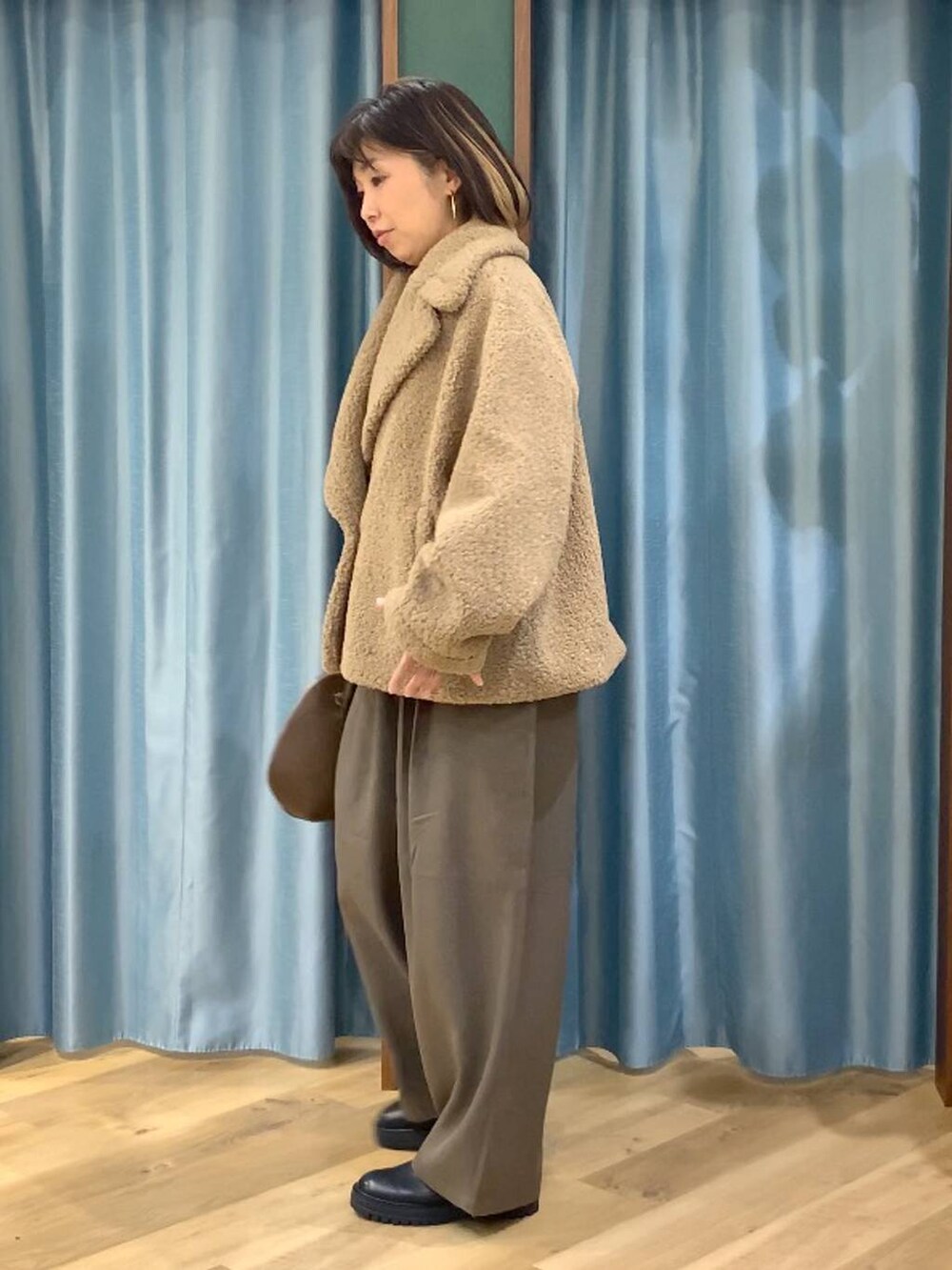 ブラック系のブーツ、ベージュ系のピーコート、ブラウン系のトートバッグを着用したレディースの秋コーディネートの4枚目の写真