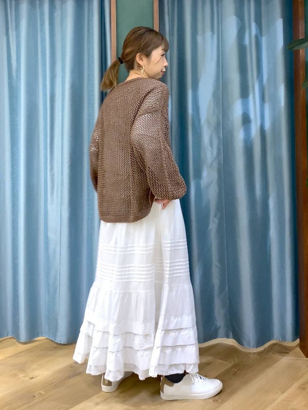 ブラウン系のスニーカー、ブラウン系のニット/セーター、ホワイト系のスカートを着用したレディースの冬コーディネートの8枚目の写真