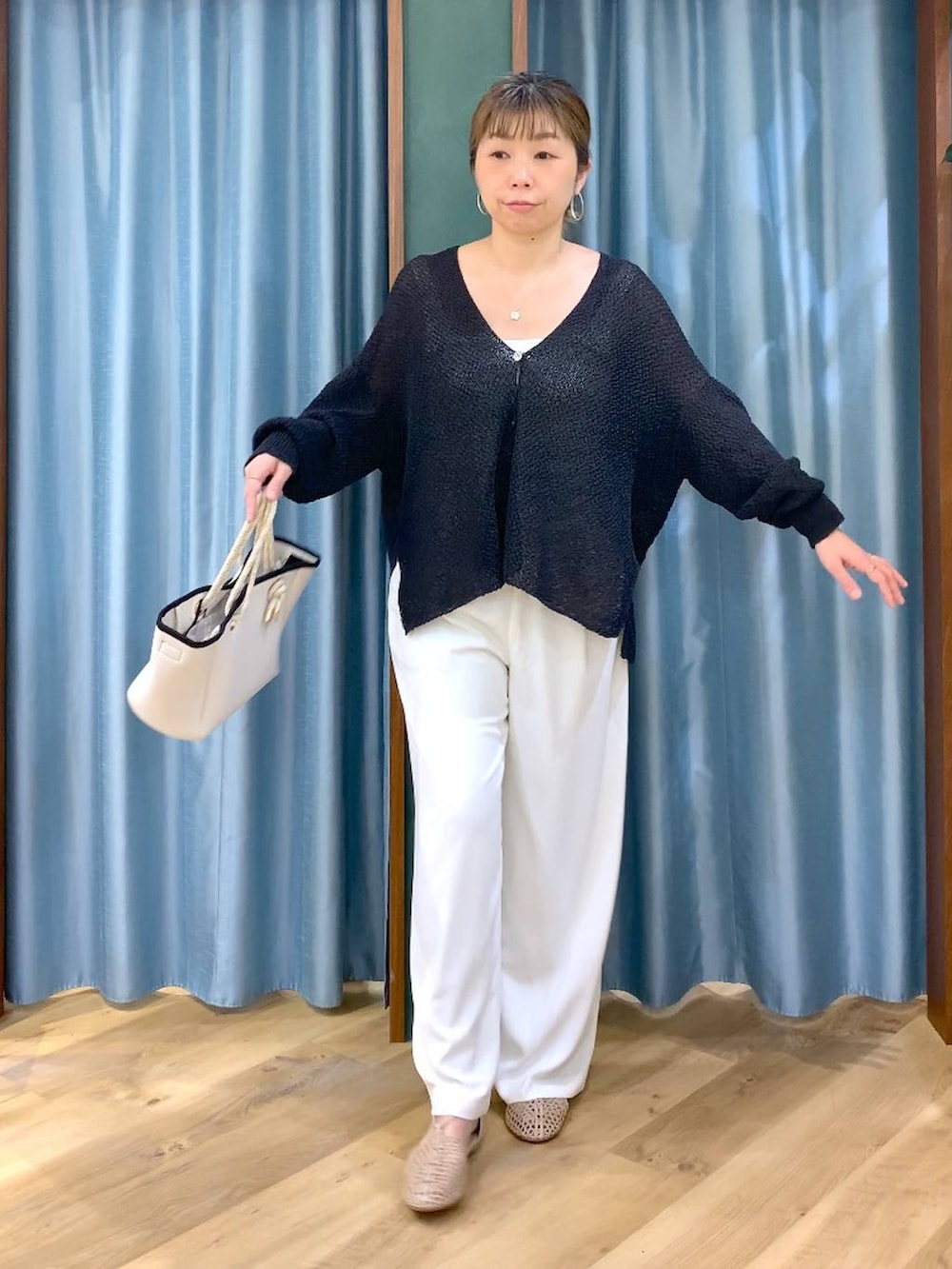 ホワイト系のスラックス、ブラック系のカーディガン/ボレロ、ホワイト系のトートバッグを着用したレディースの春コーディネートの5枚目の写真