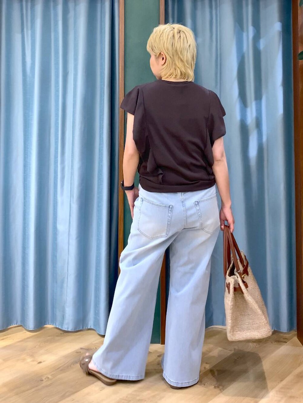ブルー系のデニムパンツ、ブラウン系のニット/セーター、ベージュ系のかごバッグを着用したレディースの夏コーディネートの5枚目の写真