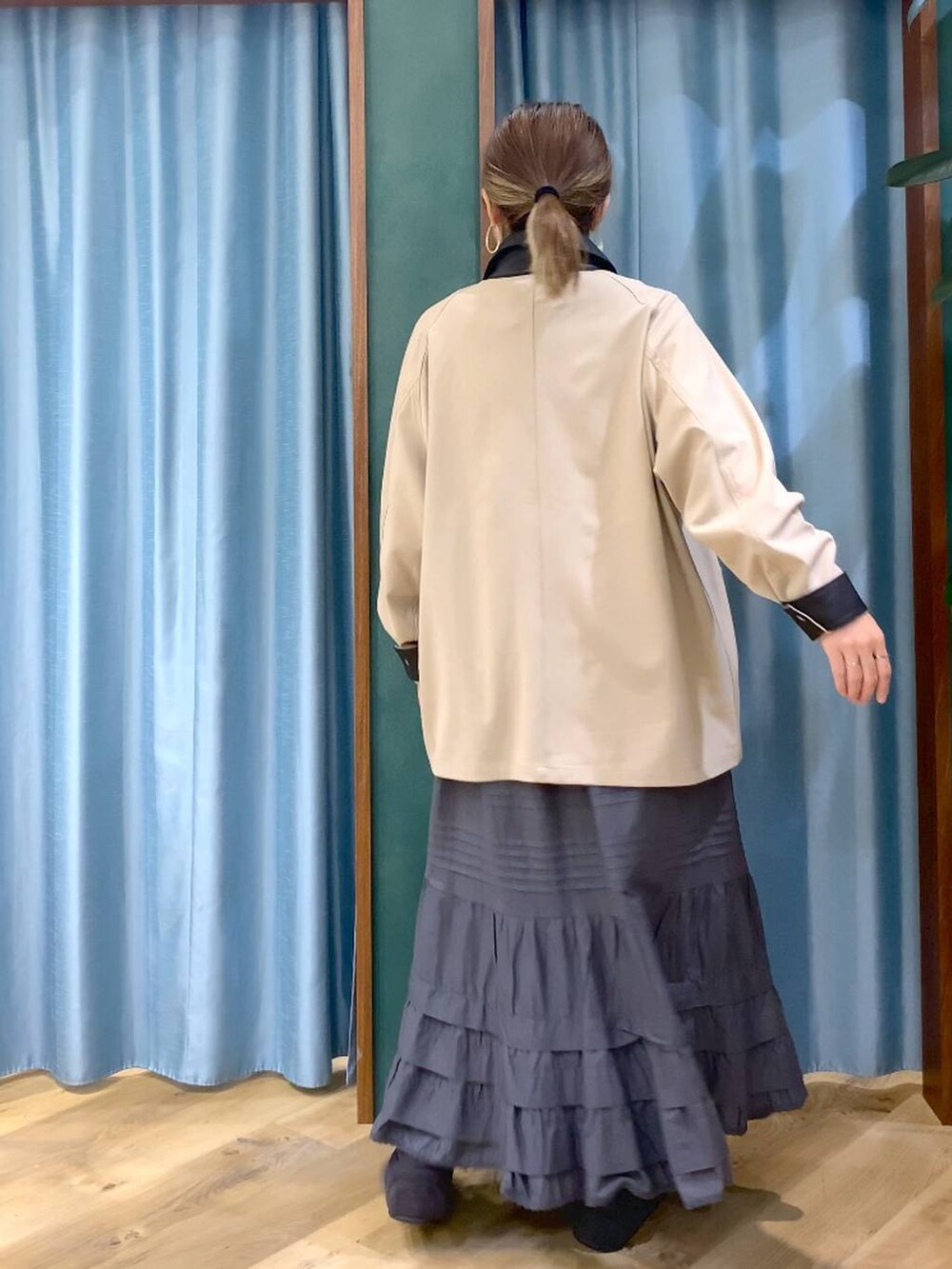 ベージュ系のカバーオール、グレー系のスカート、グレー系のスニーカーを着用したレディースの冬コーディネートの7枚目の写真