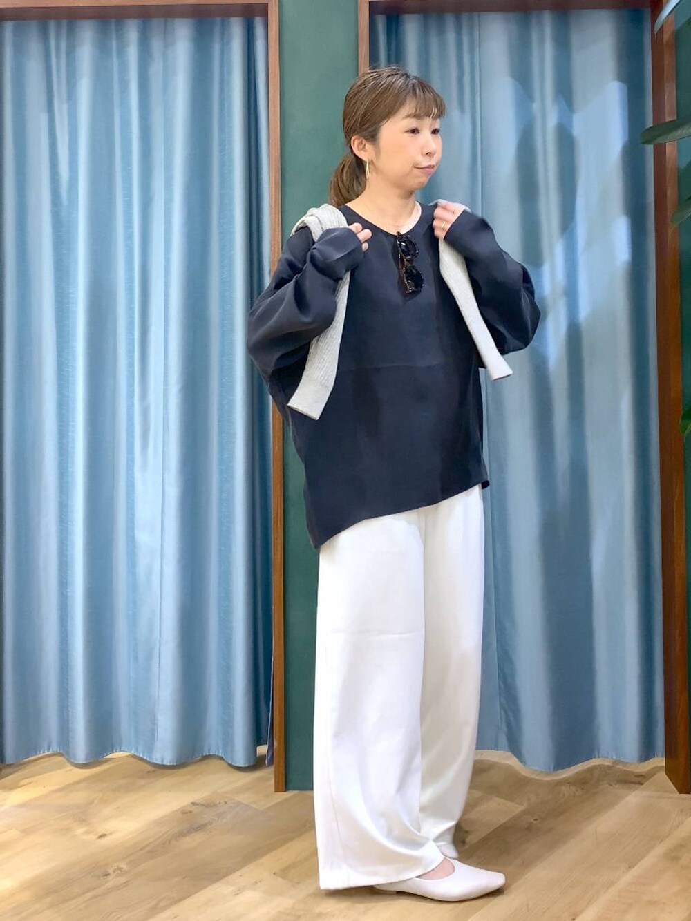 ホワイト系のスラックス、ベージュ系のカーディガン/ボレロ、ホワイト系のパンプスを着用したレディースの冬コーディネートの6枚目の写真