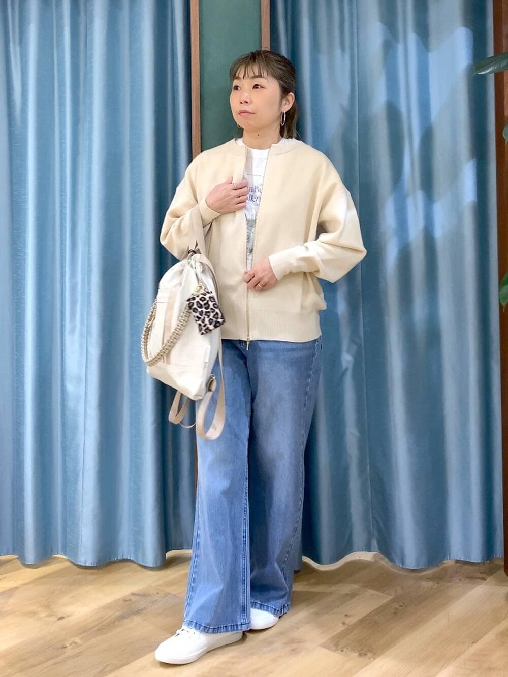 ホワイト系のカーディガン/ボレロ、ブルー系のデニムパンツ、ホワイト系のTシャツ/カットソーを着用したレディースの冬コーディネートの3枚目の写真