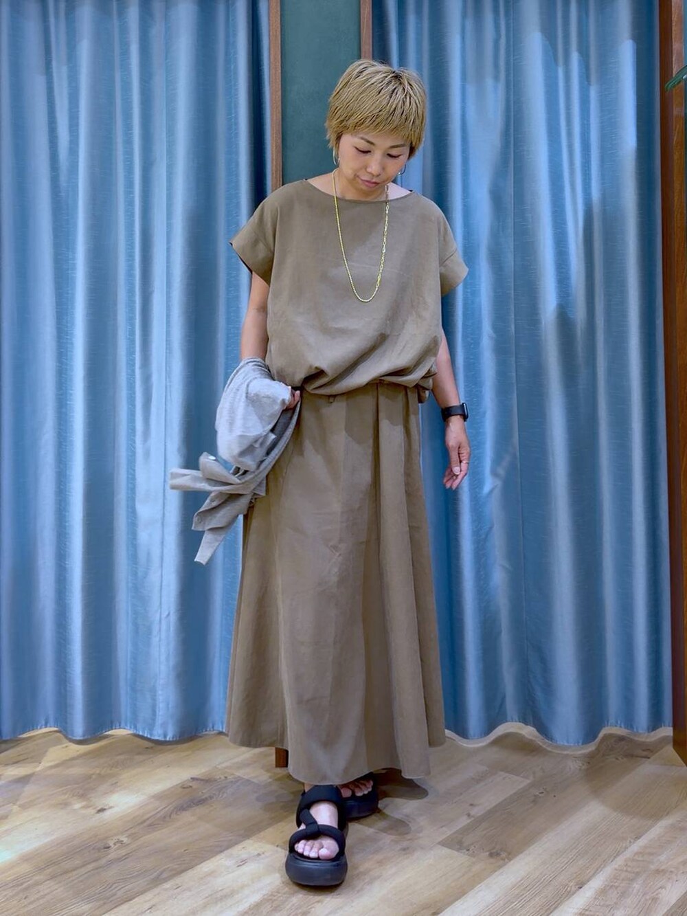 ブラック系のサンダル、ベージュ系のシャツ/ブラウス、グレー系のカーディガン/ボレロを着用したレディースの夏コーディネートの2枚目の写真