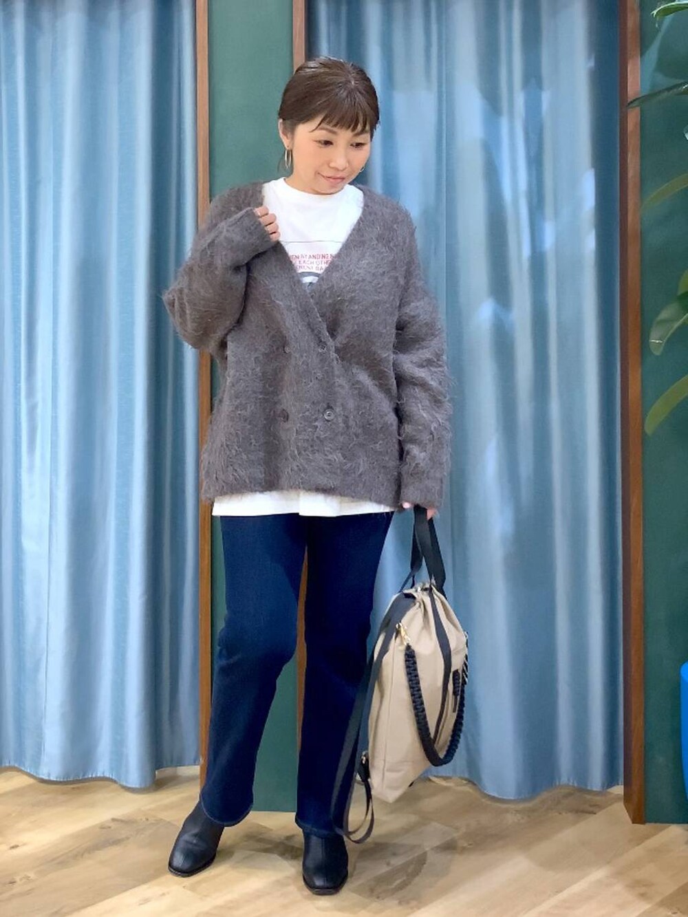 ブルー系のデニムパンツ、ブラック系のブーツ、ホワイト系のTシャツ/カットソーを着用したレディースの秋コーディネートの8枚目の写真