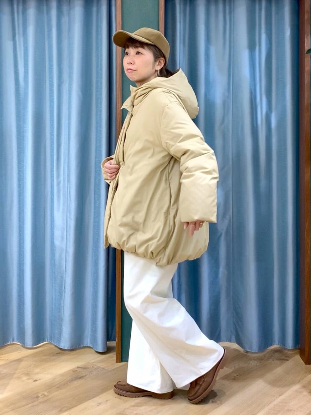 ベージュ系のダウンジャケット/コート、ブラウン系のローファー、グレー系のニット/セーターを着用したレディースの秋コーディネートの2枚目の写真