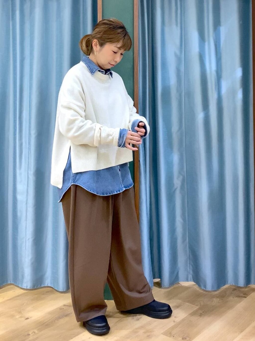 ブルー系のシャツ/ブラウス、ホワイト系のニット/セーター、ブラック系のブーツを着用したレディースの冬コーディネートの5枚目の写真