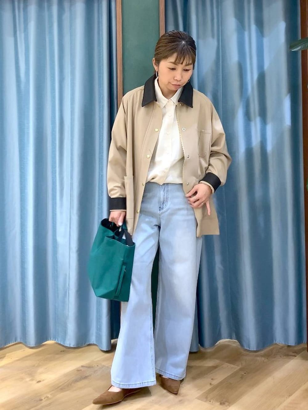 グリーン系のトートバッグ、ブルー系のデニムパンツ、ベージュ系のカバーオールを着用したレディースの冬コーディネートの3枚目の写真