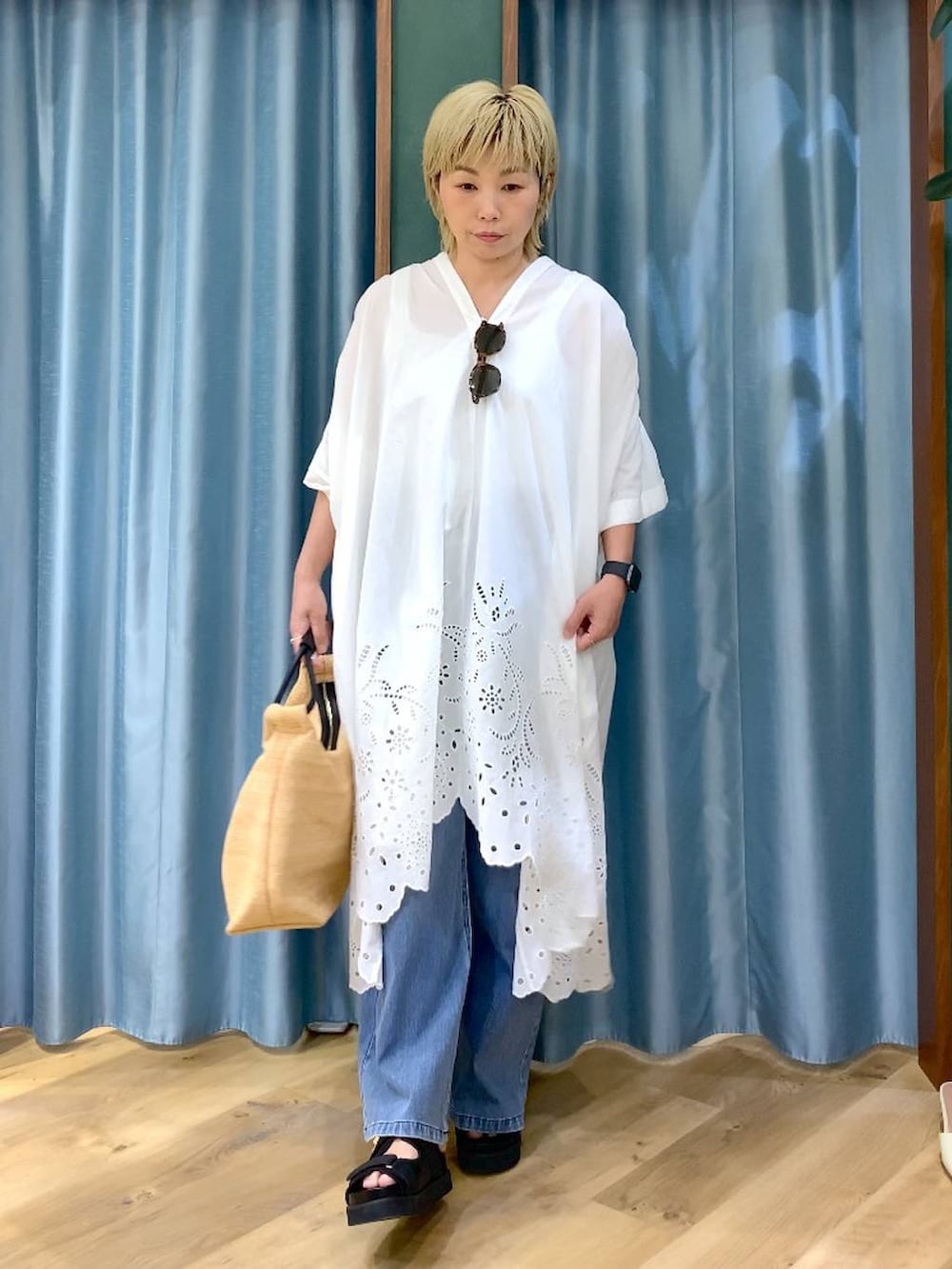 ブルー系のデニムパンツ、ブラック系のサンダル、ベージュ系のトートバッグを着用したレディースの夏コーディネートの3枚目の写真