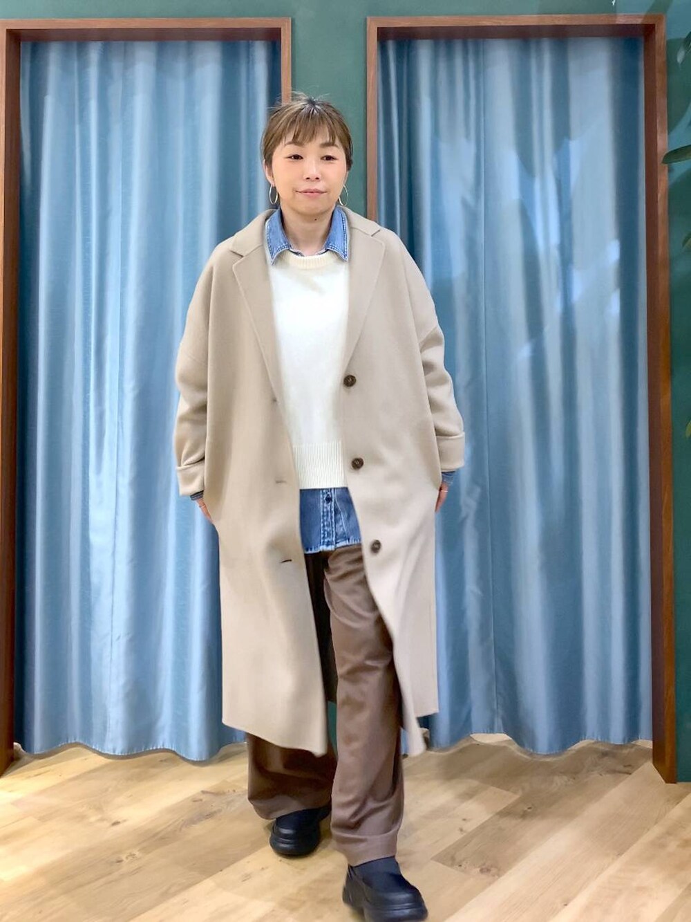 ブルー系のシャツ/ブラウス、ベージュ系のチェスターコート、ホワイト系のニット/セーターを着用したレディースの冬コーディネートの9枚目の写真