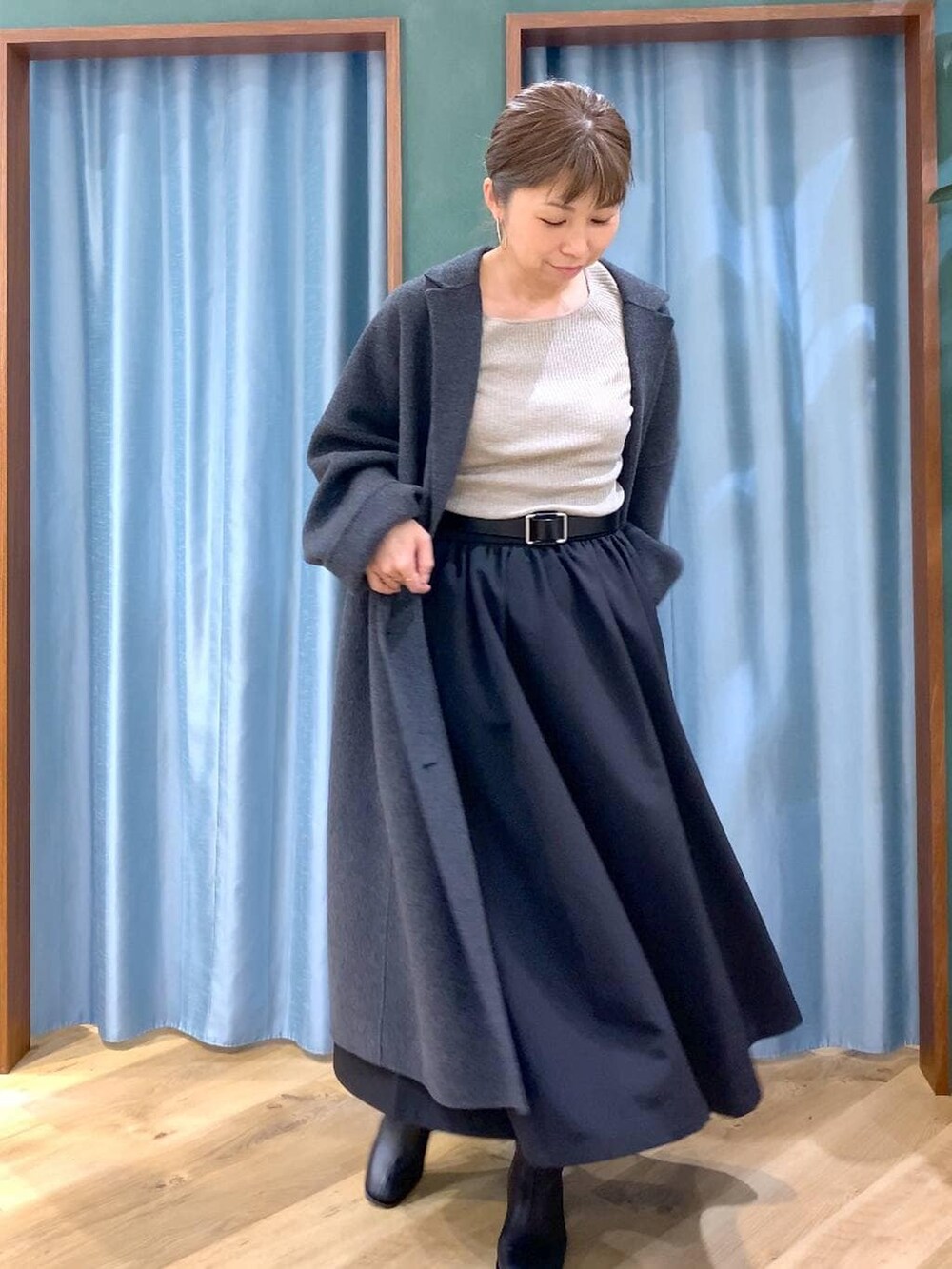 グレー系のチェスターコート、ブラック系のブーツ、ベージュ系のニット/セーターを着用したレディースの冬コーディネートの8枚目の写真