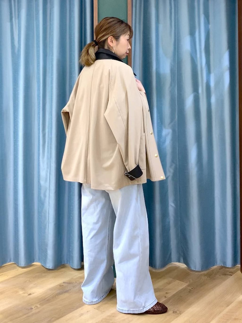 ブルー系のデニムパンツ、ブラウン系のニット/セーター、ベージュ系のカバーオールを着用したレディースの春コーディネートの3枚目の写真