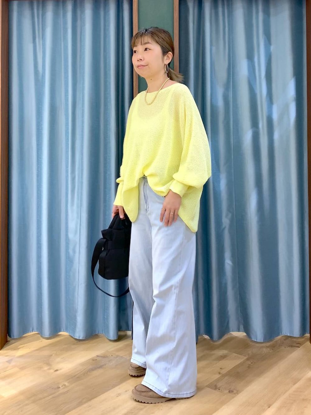 ブラック系のショルダーバッグ、ベージュ系のローファー、ブルー系のデニムパンツを着用したレディースの春コーディネートの4枚目の写真