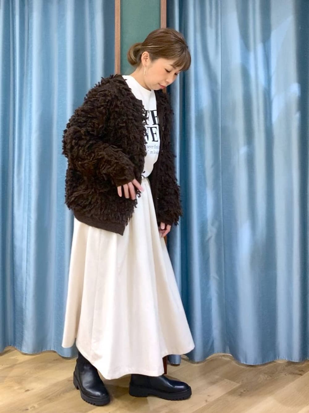 ブラック系のブーツ、ホワイト系のスカート、ブラウン系のカーディガン/ボレロを着用したレディースの冬コーディネートの3枚目の写真