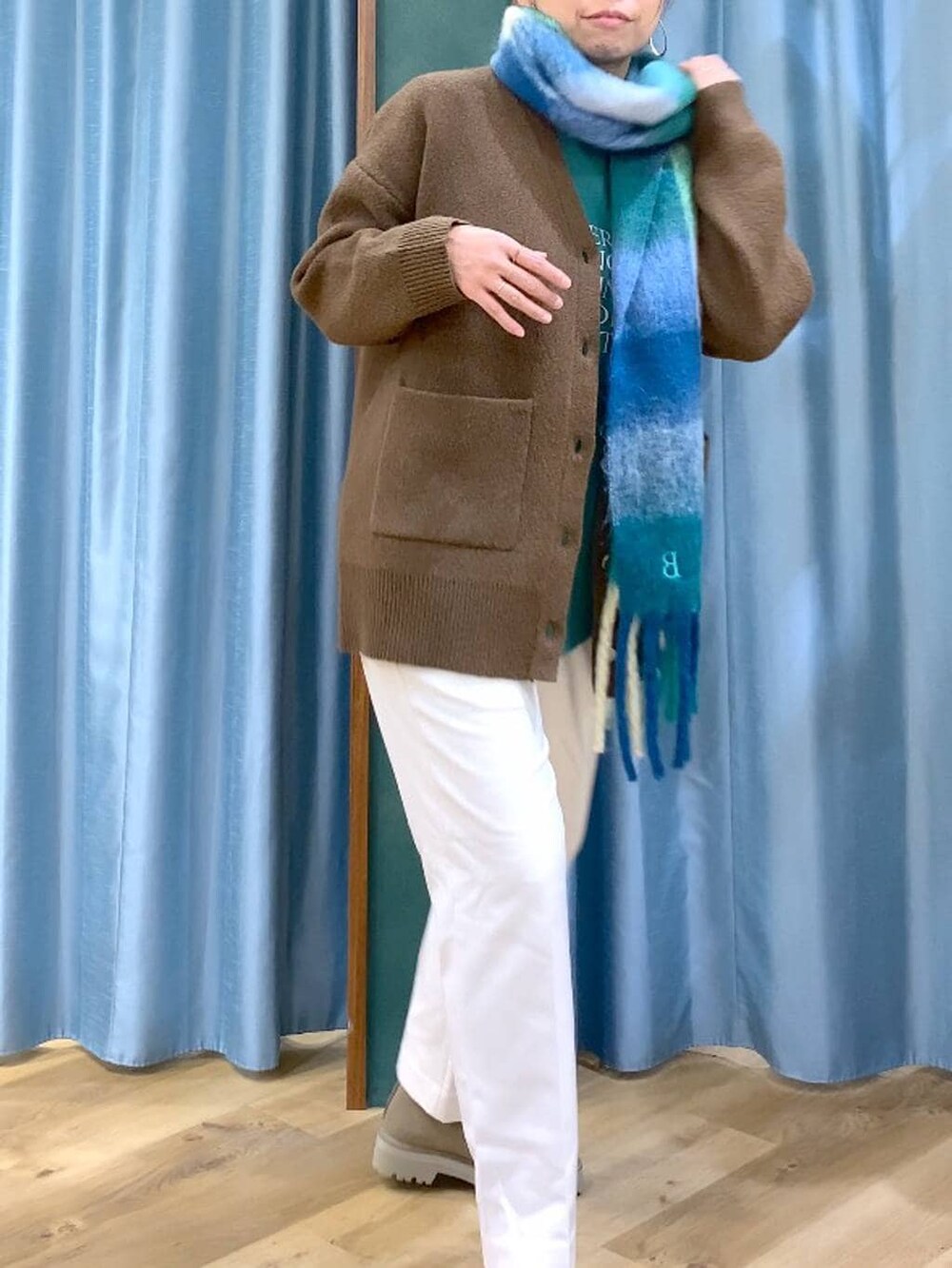 ベージュ系のブーツ、グリーン系のTシャツ/カットソー、ホワイト系のスラックスを着用したレディースの冬コーディネートの6枚目の写真