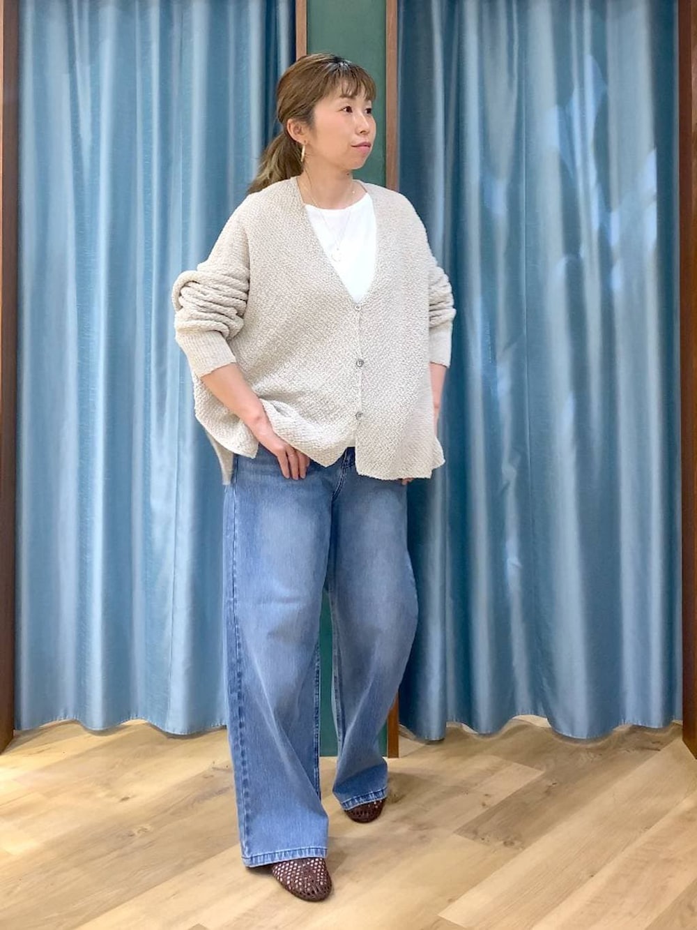 ブルー系のデニムパンツ、ホワイト系のTシャツ/カットソー、ベージュ系のカーディガン/ボレロを着用したレディースの春コーディネートの3枚目の写真