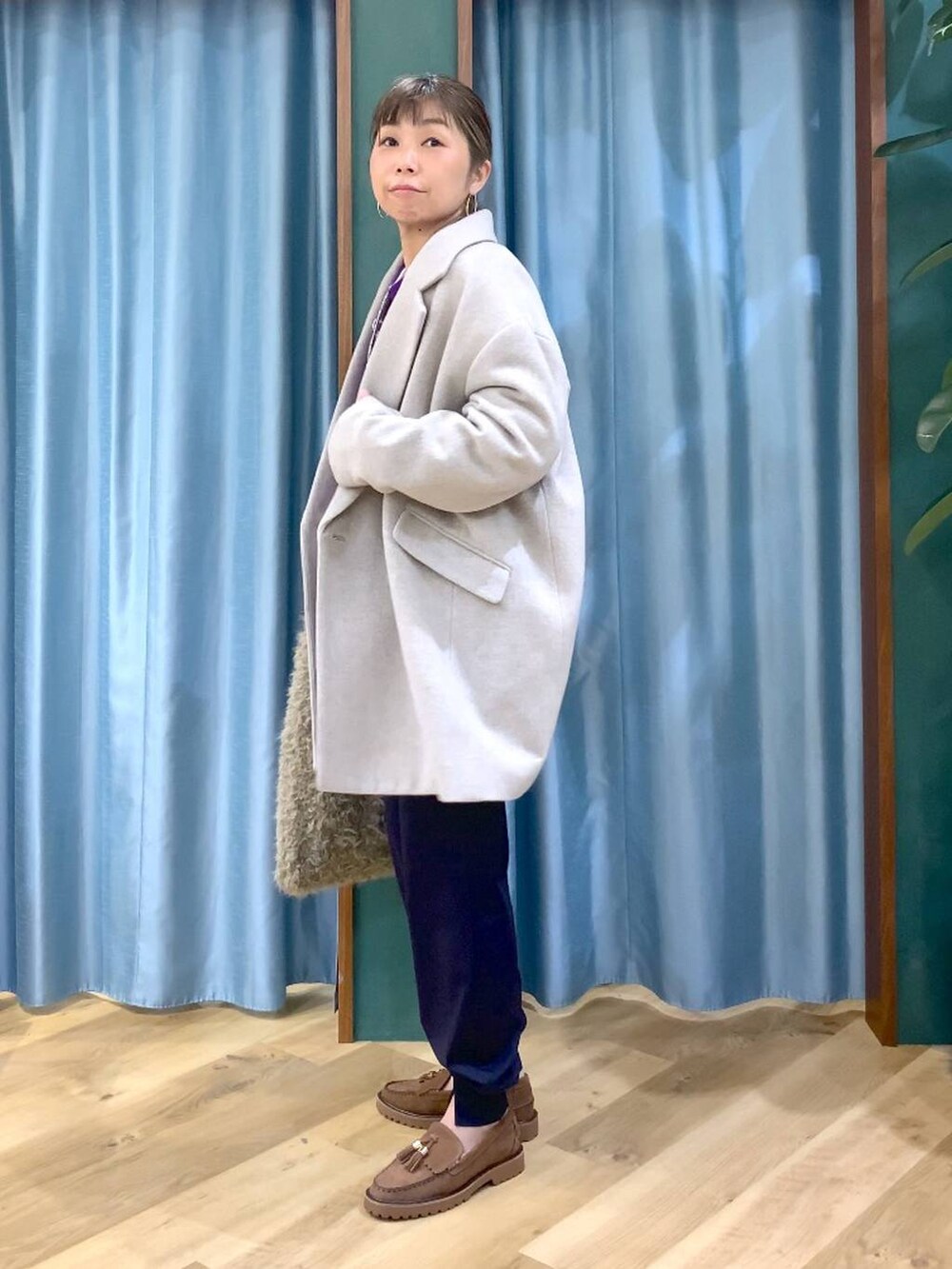 パープル系のニット/セーター、ベージュ系のピーコート、ベージュ系のハンドバッグを着用したレディースの秋コーディネートの5枚目の写真