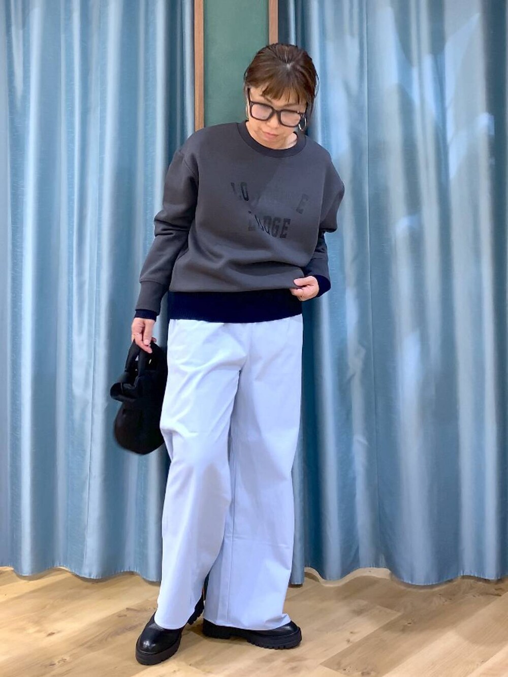 ブラック系のブーツ、ブラック系のショルダーバッグ、ブルー系のニット/セーターを着用したレディースの秋コーディネートの3枚目の写真